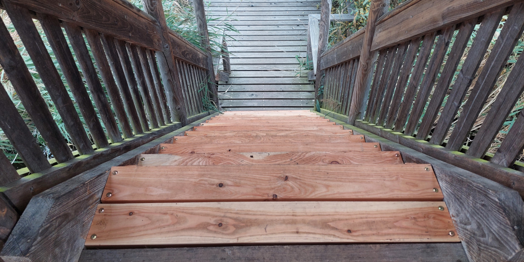 Pohled ze shora na nové stupně schodiště z modřínového dřeva.